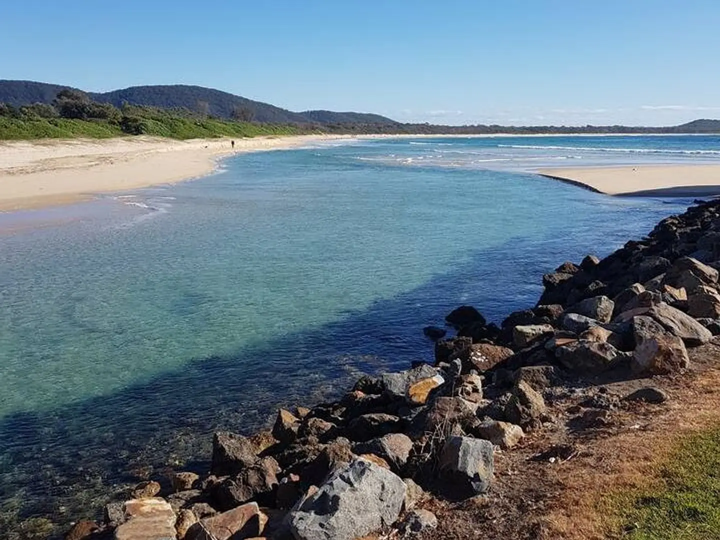 Clear water at the Killick Creek estuary, with rocks and the beach beyond
