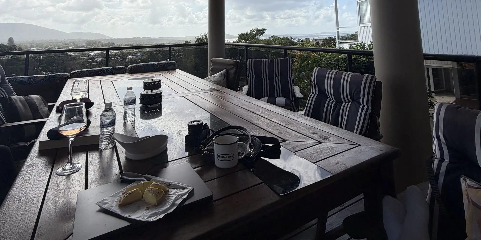 A glass of wine and something to nibble on the long deck table, the hills beyond