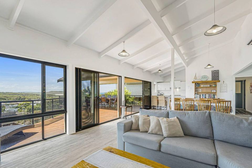 Living room with grey sofas and sliding doors open to the deck, the dining table beyond